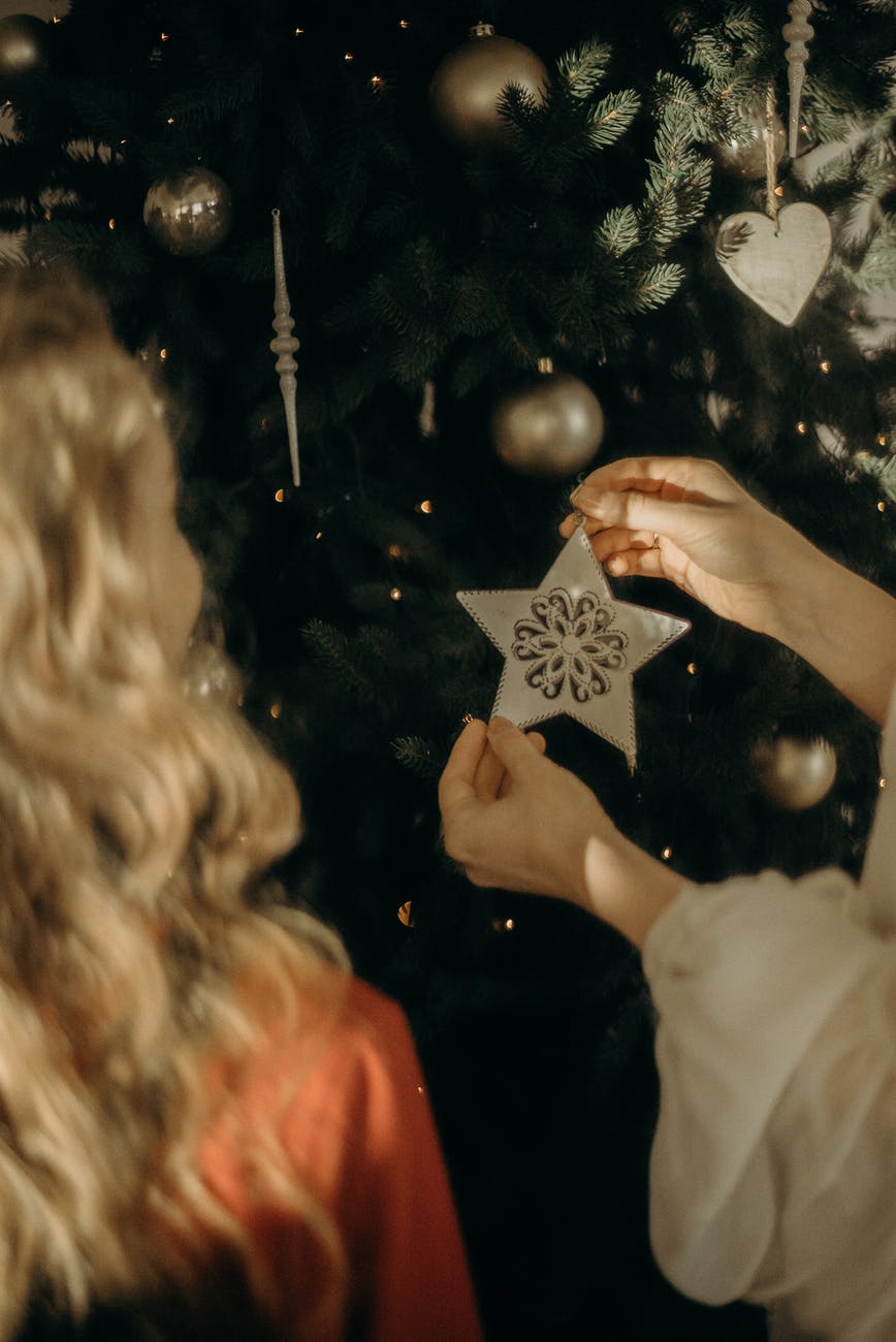 girls putting ornaments on a christmas tree